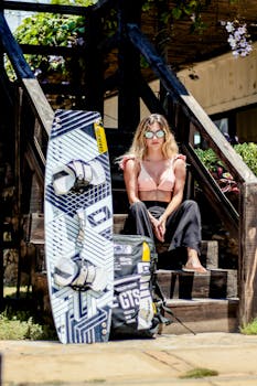 A stylish woman sitting with a kiteboard on stairs in sunny Adicora, Venezuela.