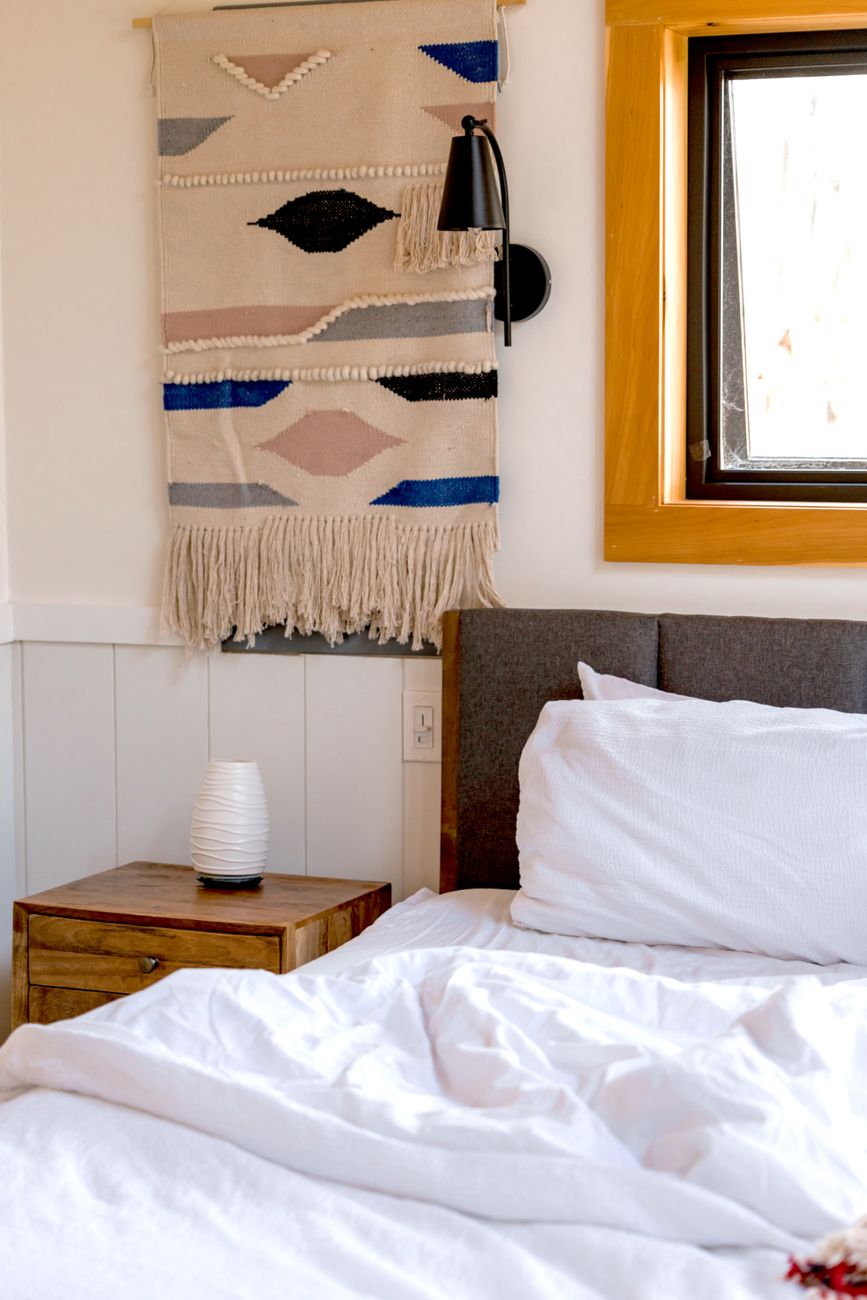 A woven installation placed above a console, with enough empty wall around it to make the texture read from across the room.