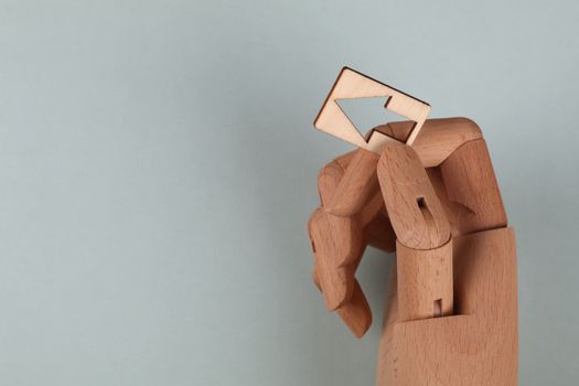 Wooden mannequin hand holding a wooden arrow against a light blue backdrop, representing direction and guidance.