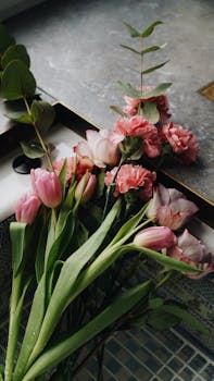 A beautiful bouquet of pink tulips and carnations lying on a kitchen sink, perfect for floral decor.