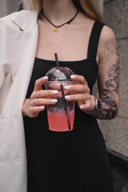 Close-Up Shot of a Tattooed Woman Holding a Beverage