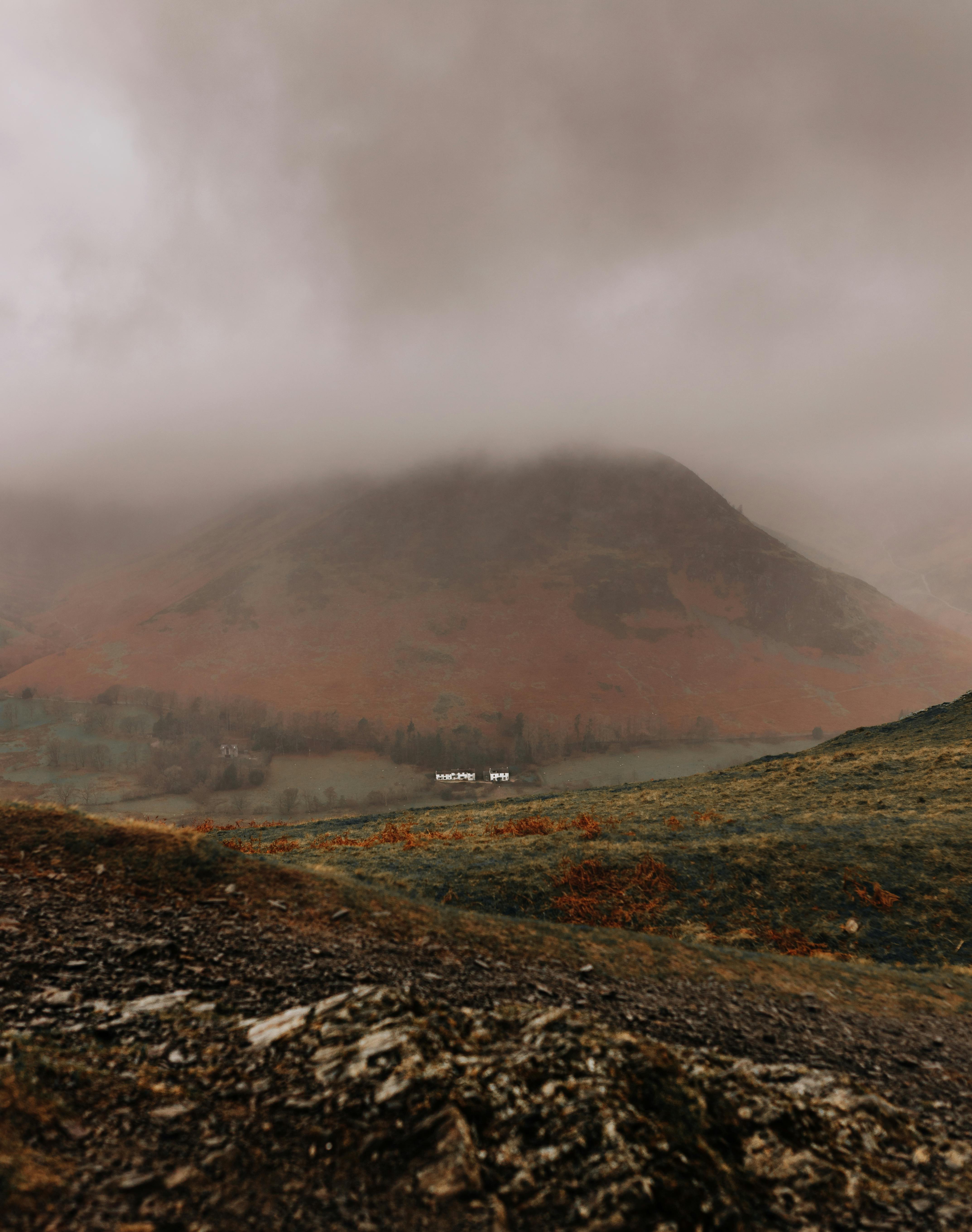 A serene mountain landscape shrouded in clouds and mist, creating a dramatic atmosphere.