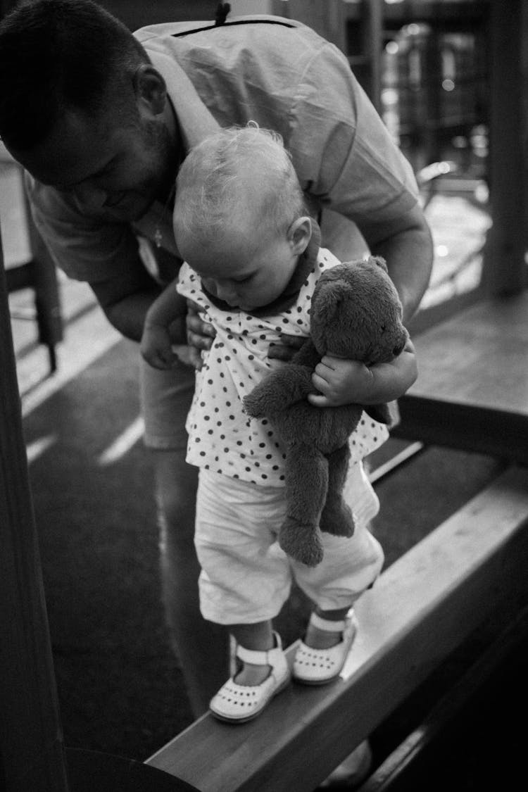 A Man Teaching A Baby To Walk