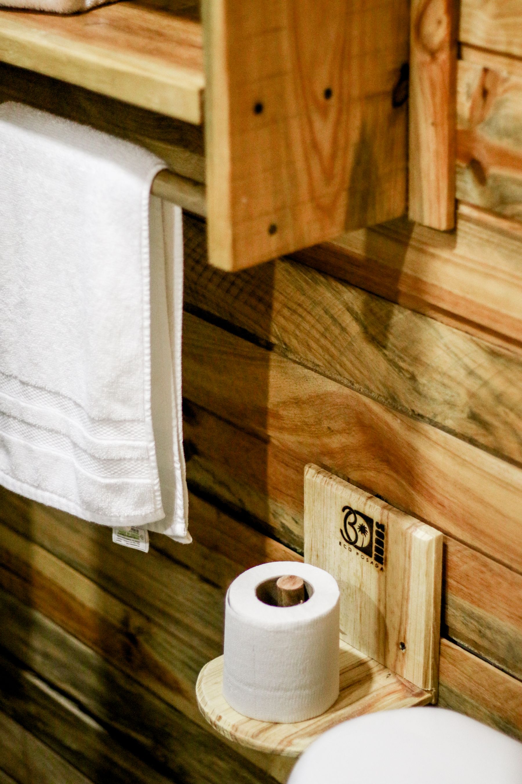 Rustic bathroom with wooden shelves holding towels and toilet paper