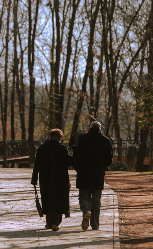 Free A senior couple walking in a park in Tirana, Albania during autumn, echoing love and companionship. Stock Photo
