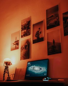A warm-lit home office with a laptop and artistic wall photos, creating a cozy atmosphere.