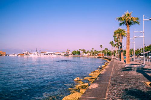Free A vibrant coastal waterfront with palm trees, boats, and clear skies, perfect for summer travel. Stock Photo