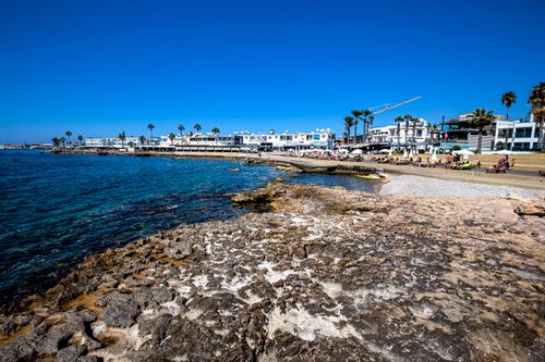 Free Beautiful coastal town with rocky shore and clear blue sea under a bright sky, ideal for vacation Stock Photo