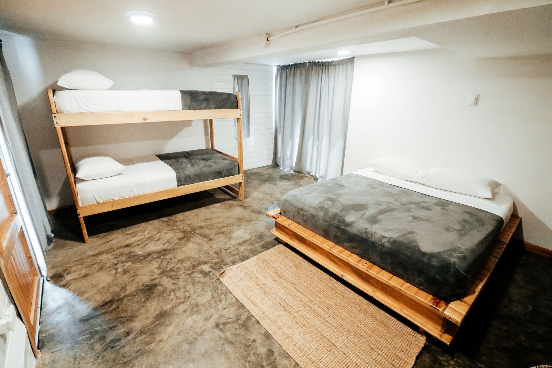 Compact shared bedroom with a timber bunk bed, separate low platform bed and long curtains