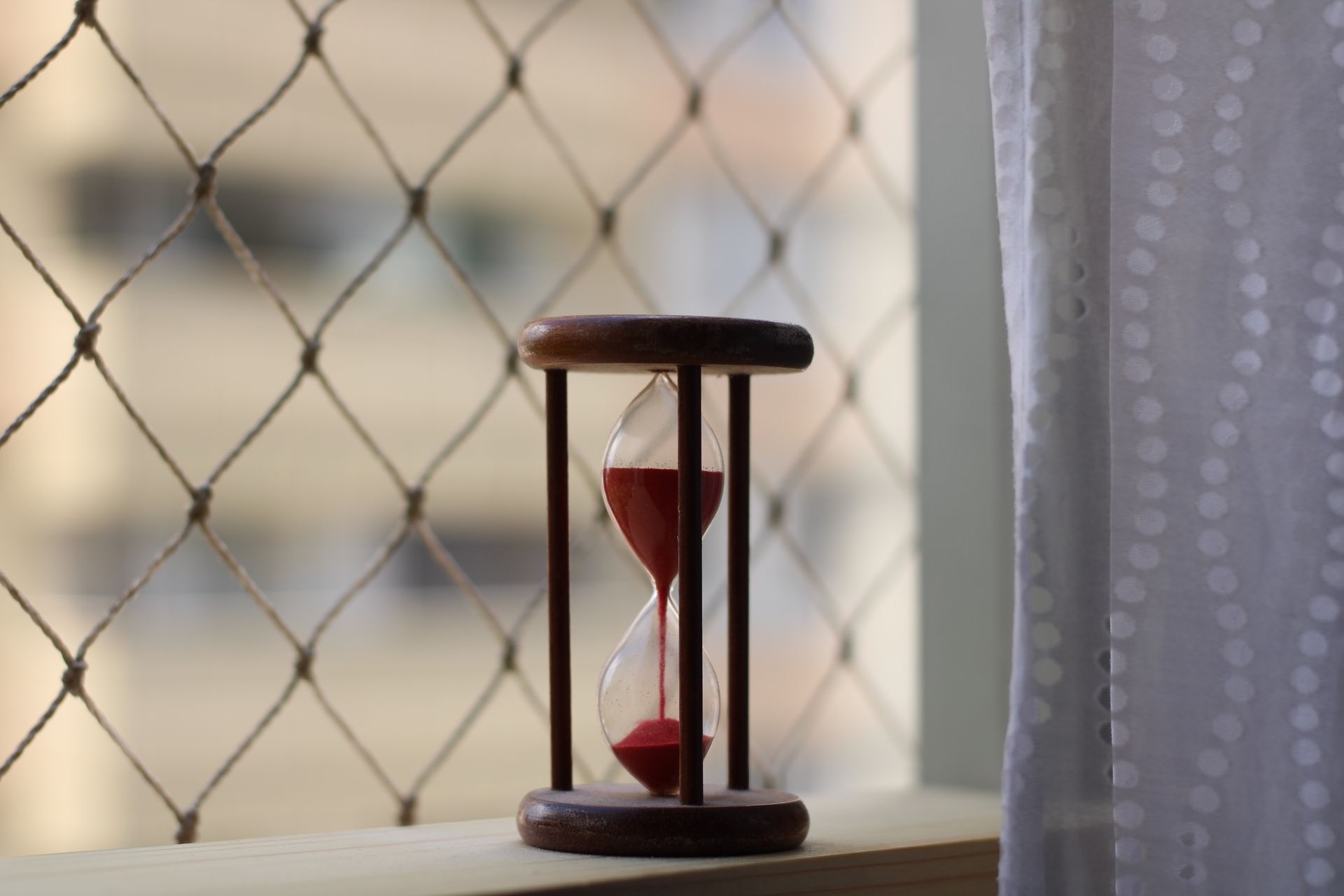 A close-up shot of a wooden hourglass on a window sill with gentle lighting, conveying a sense of time and tranquility.