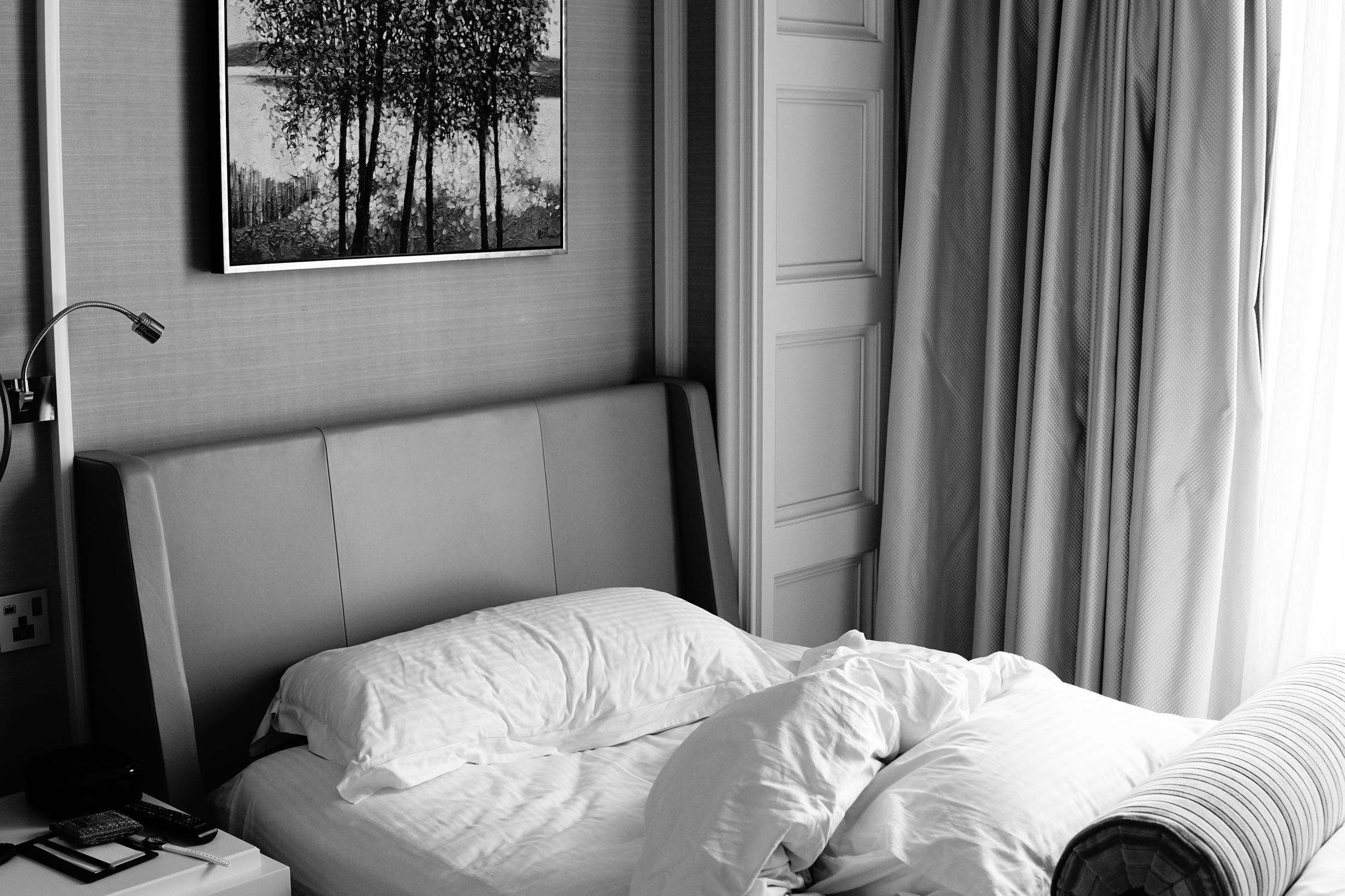 A stylish bedroom with monochrome decor, featuring a bed and artistic wall art.