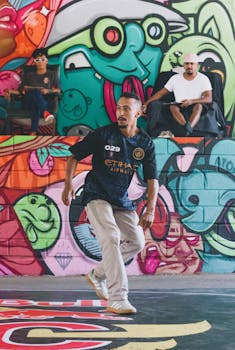 A dancer showcases hip-hop moves against vibrant street art, capturing urban culture.