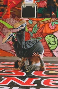 Energetic breakdancer performing a headspin in front of colorful graffiti indoors.