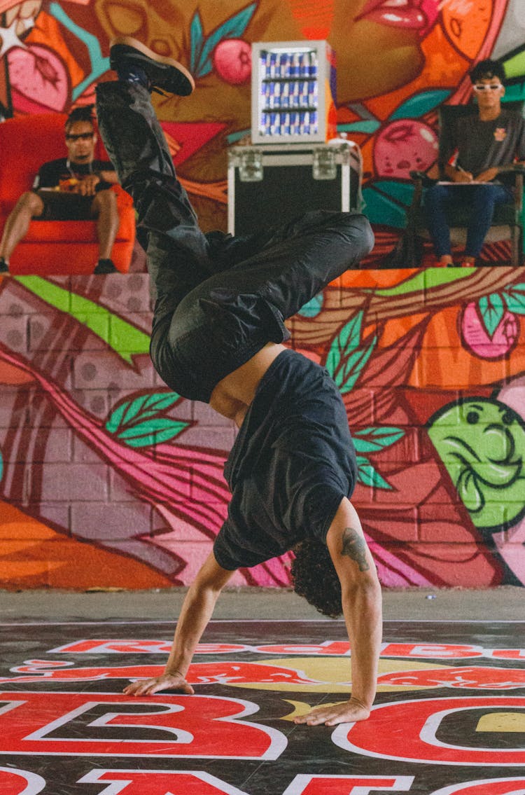 A Person Break Dancing Near A Wall With Mural
