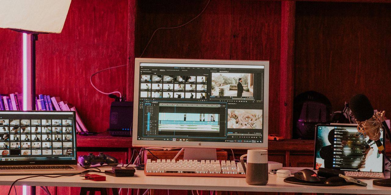 A professional video editing workspace featuring monitors, keyboard, and microphones in a studio setting.