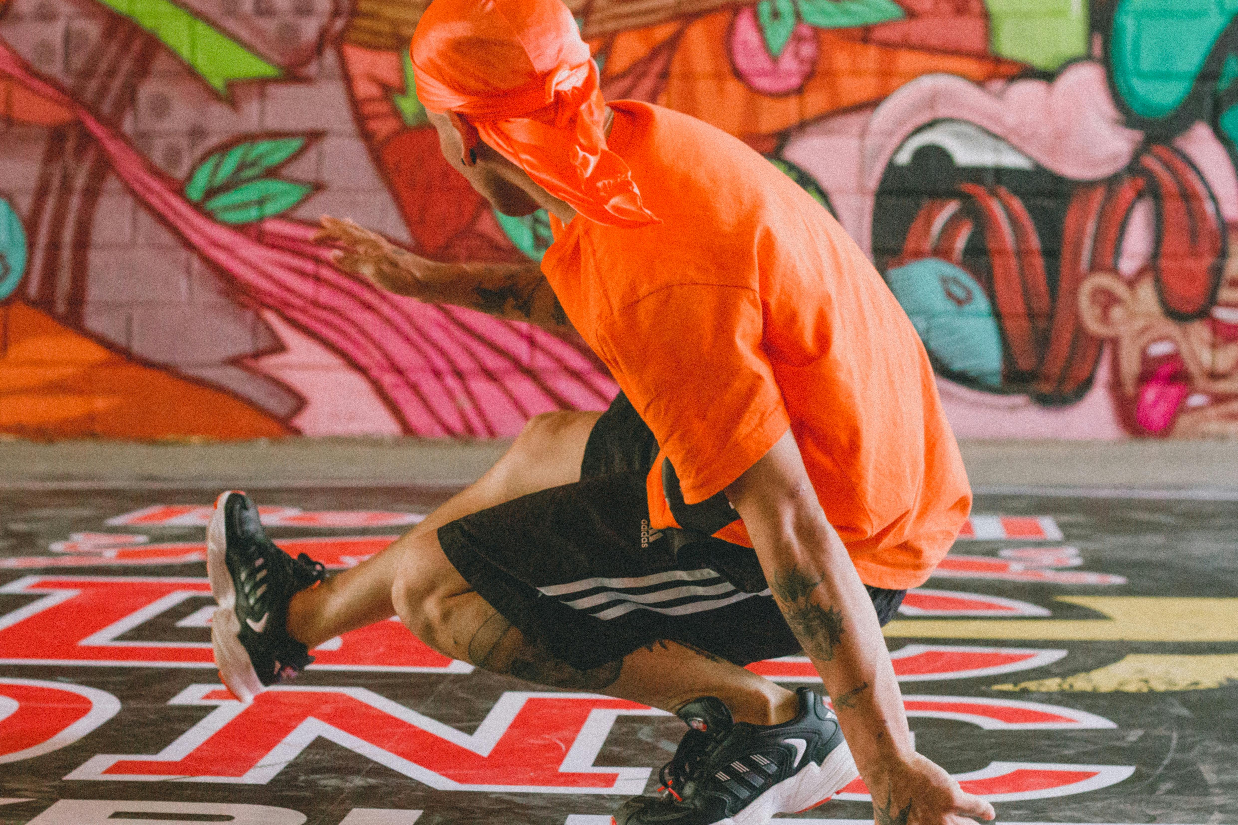 A Person in Orange T shirt and Black Shorts Dancing Free Stock Photo