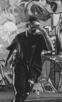 Energetic dancer performing street dance against a graffiti backdrop.