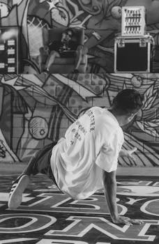 Dynamic shot of a breakdancer performing in front of a colorful urban graffiti mural.
