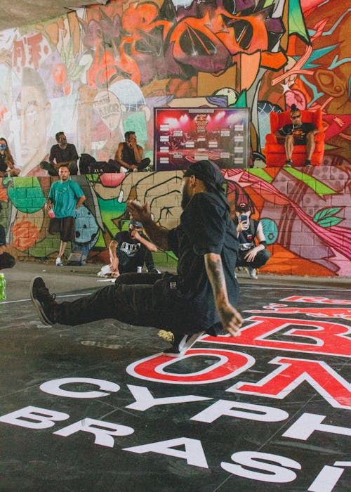 Free Energetic breakdance performance amidst vibrant street art and graffiti, highlighting urban culture. Stock Photo