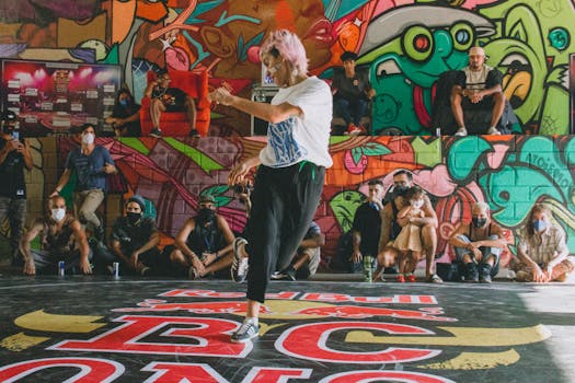 Energetic street dance performance captured in a colorful urban setting with graffiti art and an audience.
