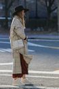 Woman in Brown Coat and Red Skirt Standing on Road