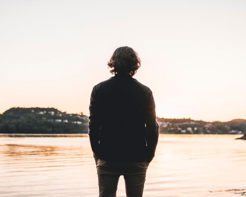 A person standing by a lake at sunset, exuding calmness and reflection.