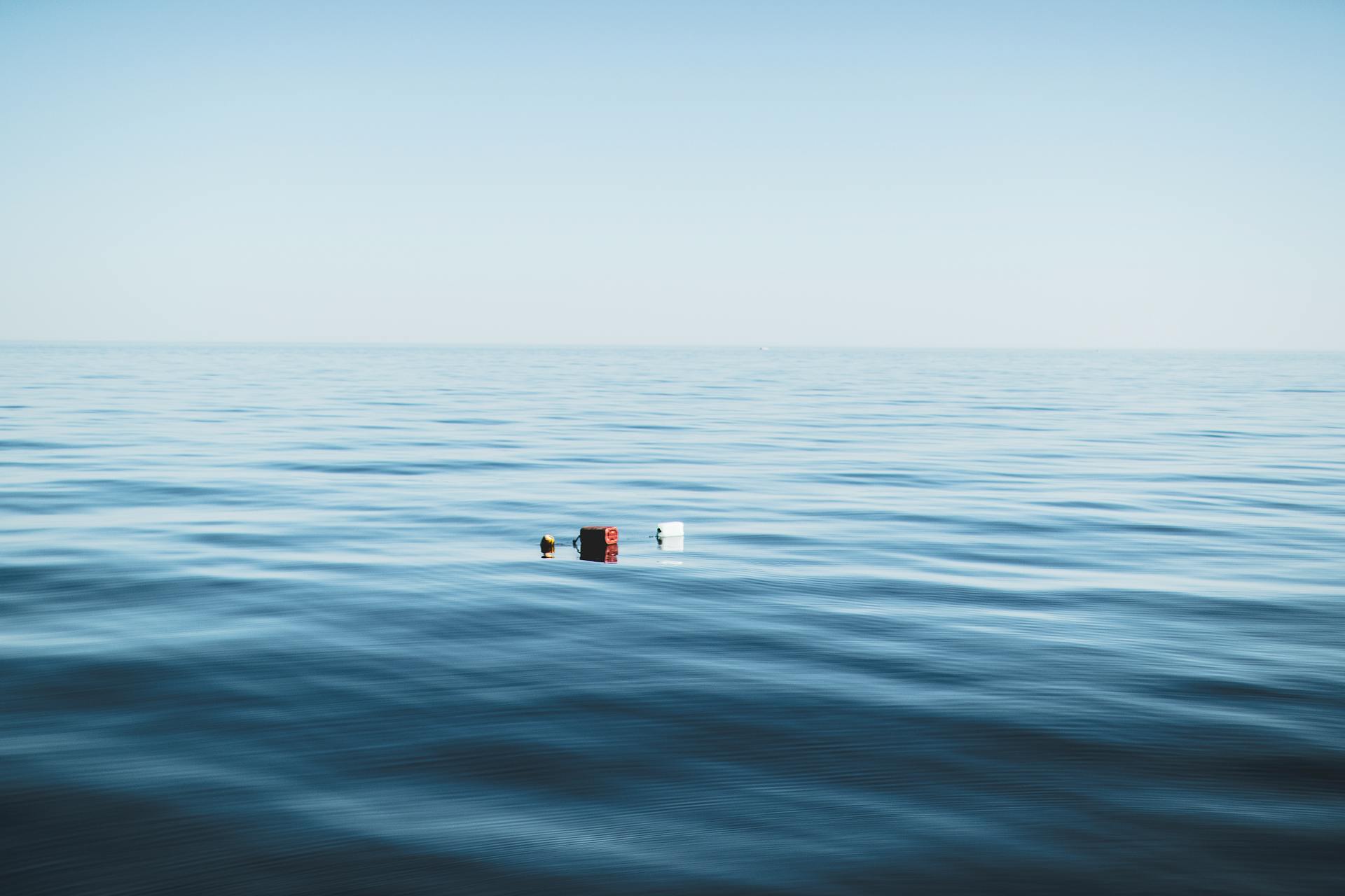 Calm ocean view with colorful floating objects under a clear sky.