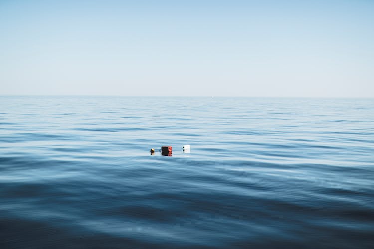 Three Red And White Floating Objects On Water