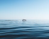 晴朗的蓝天下，一艘孤独的船航行在平静的海面上