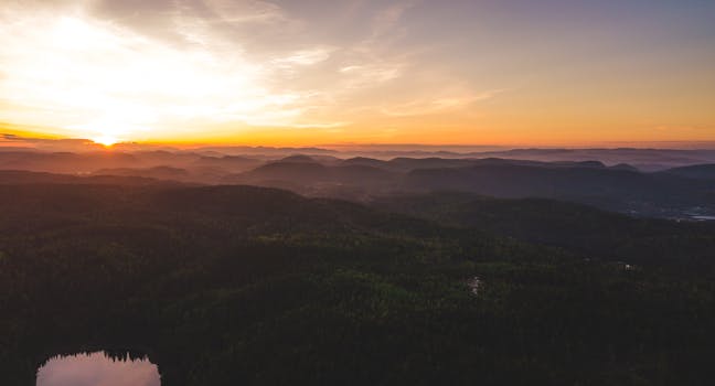 在日落时分充满活力的天空下，连绵起伏的山丘和山谷显得格外宁静