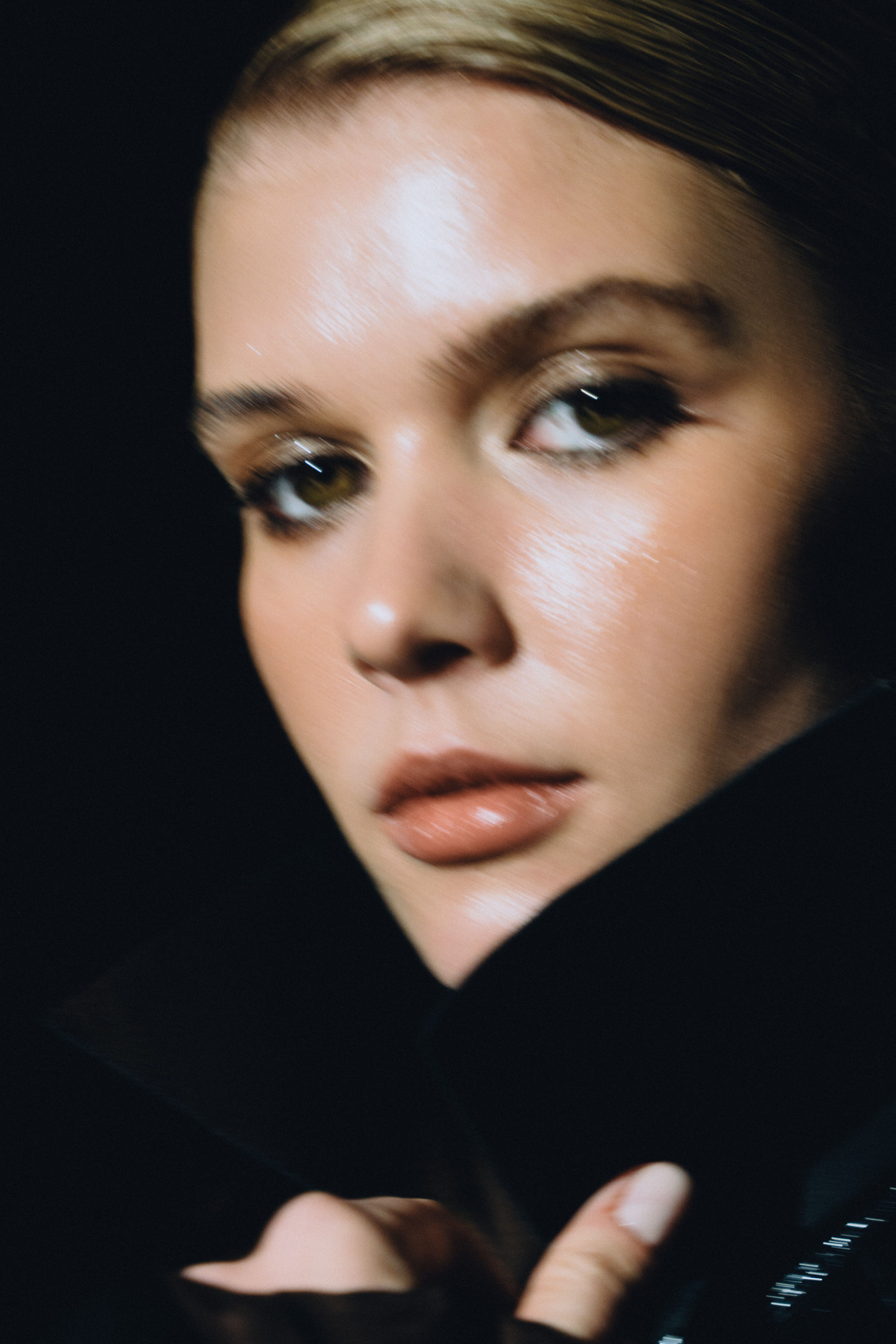 skin tone - Close-up blurred portrait of a woman with makeup in a dark setting, conveying a mysterious and artistic vibe.