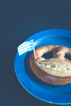A classic Bavarian pretzel with a checkered flag on a blue plate.