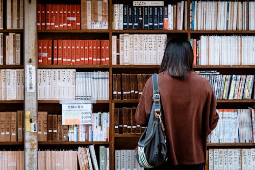 Vrouw Draagt Bruin Shirt Met Zwarte Lederen Tas Op De Voorkant Van Bibliotheekboeken