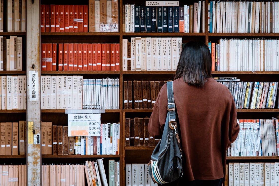 Kobieta Ubrana W Brązową Koszulę Z Czarną Skórzaną Torbą Z Przodu Książek Bibliotecznych