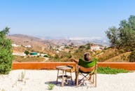 一名男子在露台上放松身心，俯瞰着晴朗天空下科尔多瓦风景优美的山丘与山谷