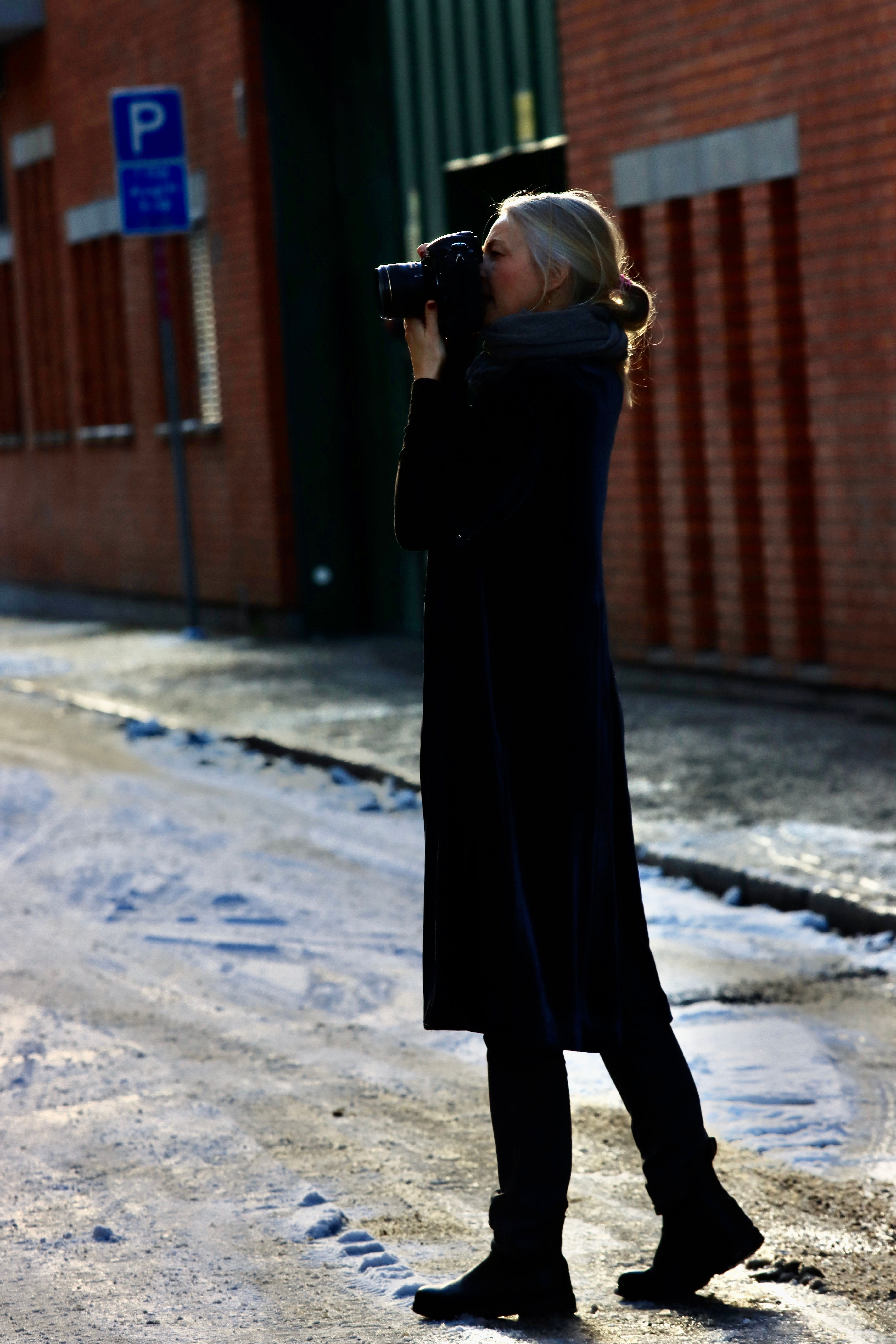 Artistic shot of a woman photographing snowy streets in Jönköping, Sweden.