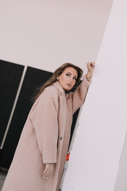 Woman in Brown Coat Posing near the Wall