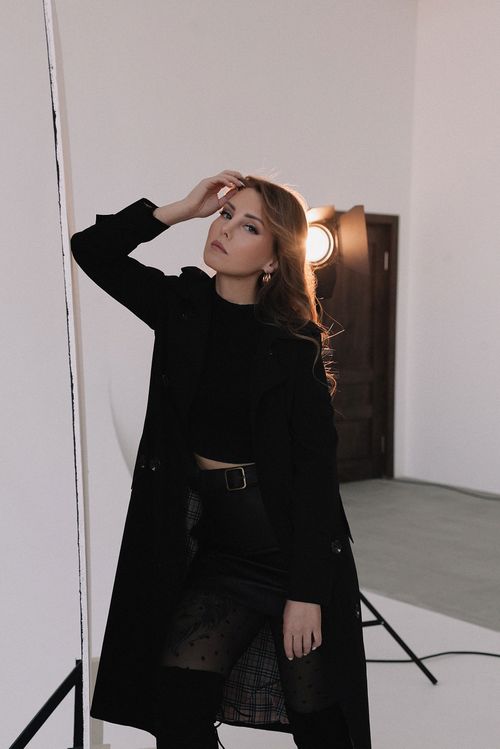 Free A stylish woman in a black coat and skirt posing in a professional studio setting. Stock Photo