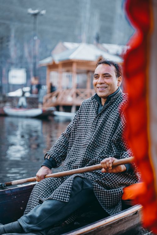 Free A man enjoys a peaceful boat ride while rowing on a serene lake, exuding happiness and contentment. Stock Photo