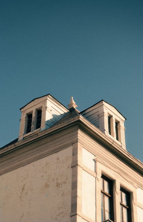 Free Low angle view of a vintage building corner with elegant twin gables under a clear sky. Stock Photo