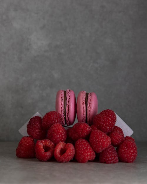 Red Raspberries and Pink Macarons on Gray Surface