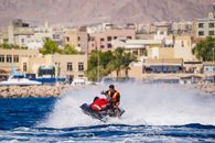 Man in Orange Vest Riding on Red and Black Personal Watercraft