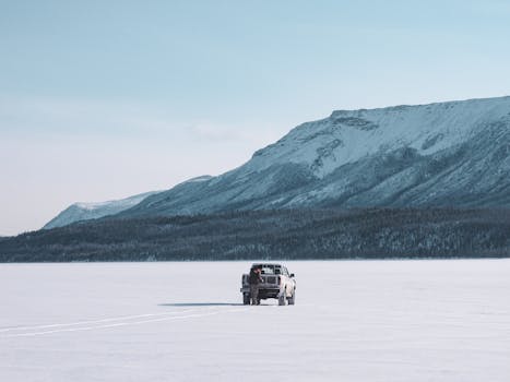 A pickup truck in a serene snowy landscape with towering mountains, perfect for adventure seekers.