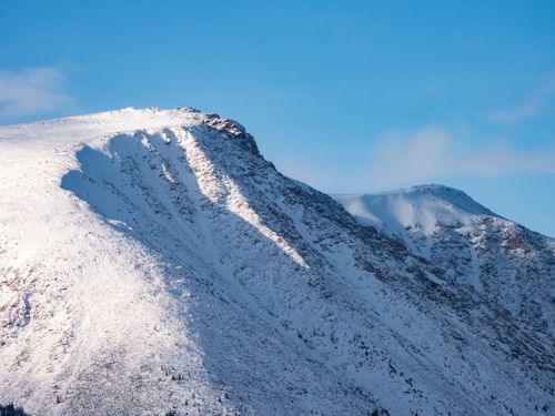 Free A stunning view of a snow-covered mountain peak under a clear blue sky. Stock Photo