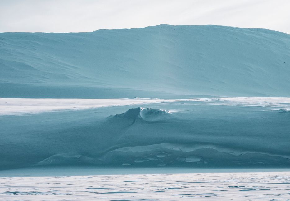 A tranquil icy landscape showcasing vast snow dunes and a serene polar climate.