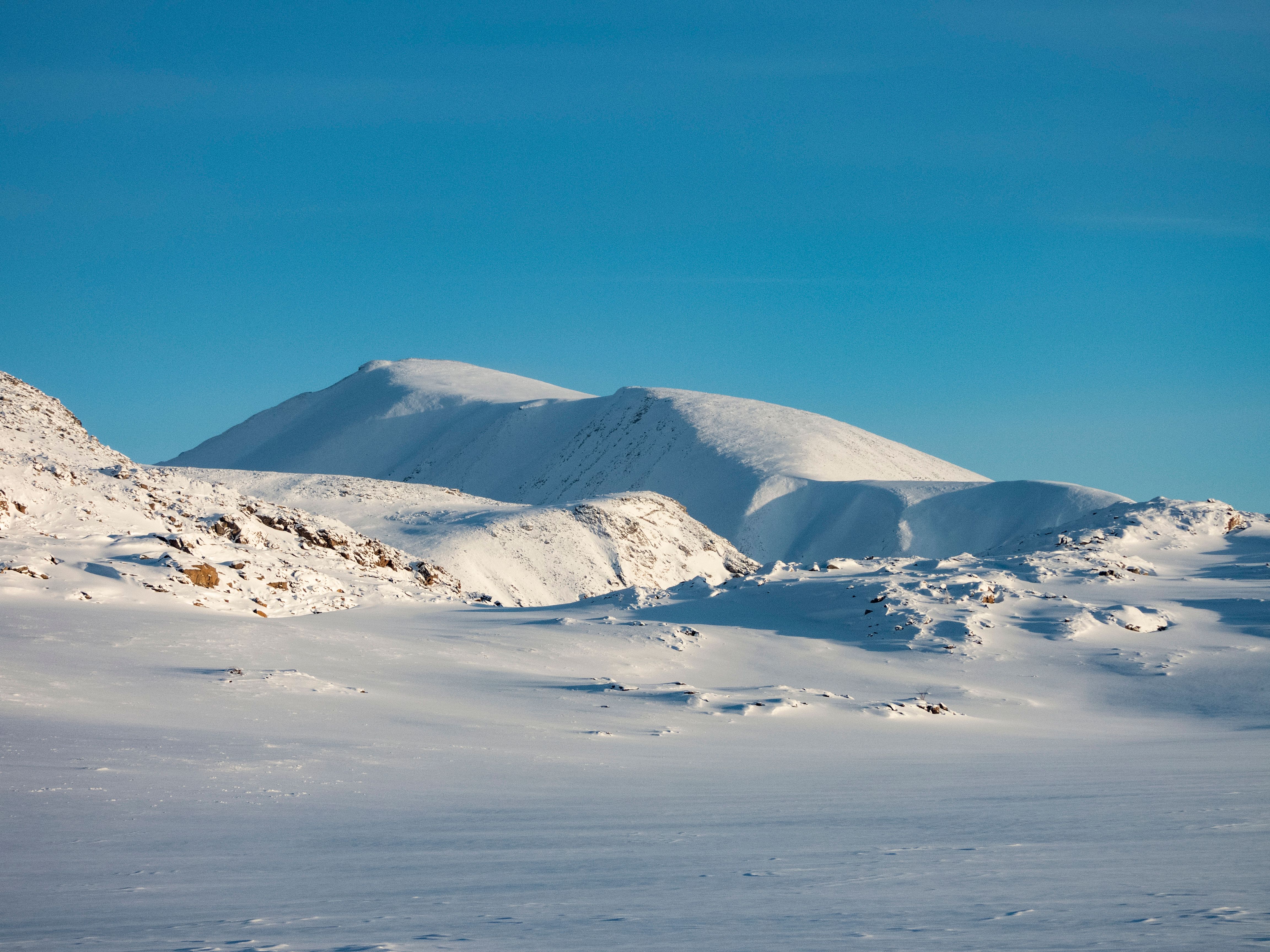 Stunning view of a snow-covered mountain landscape under a clear blue sky, capturing the serene beauty of winter.
