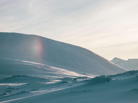A tranquil winter scene capturing snow-covered hills at sunrise, showcasing nature's beauty.