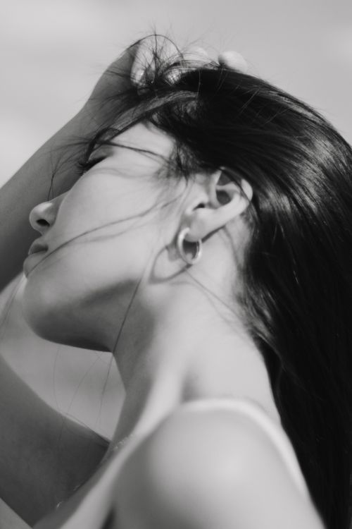 Free Artistic black and white portrait of a young woman posing with her hand on her head. Stock Photo