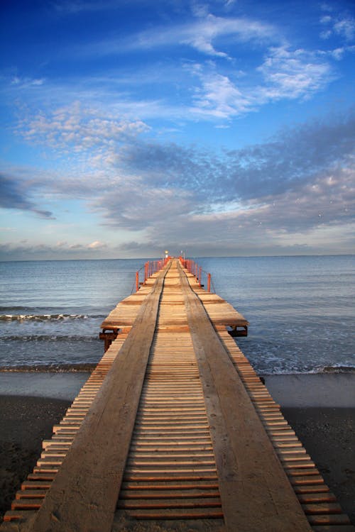 Free Brown Wooden Pier on Sea During Sunset Stock Photo