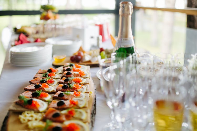 Catering Appetizers On Wooden Board Next To Empty Champagne Glasses